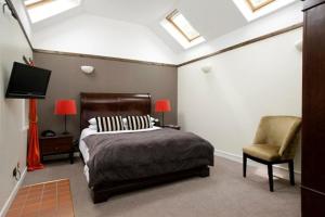 a bedroom with a bed and a chair and a tv at Sheildaig Farm in Balloch