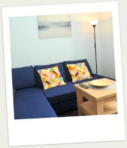 a blue couch in a living room with a table at Apartament w Alei Fontann. in Szczecin