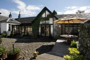 a house with a table and an umbrella at Sheildaig Farm in Balloch