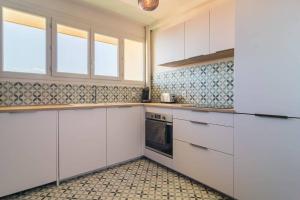 Il comprend une cuisine avec des placards blancs et du carrelage. dans l'établissement Appartement cosy et raffiné proche gare Toulon, à Toulon