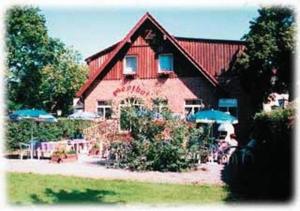 a large red barn with tables and umbrellas in front of it at Zeesener Gasthof in Königs Wusterhausen