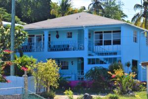a blue house with trees and flowers at Ellen Bay Cottages in Saint Philips