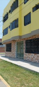 un bâtiment jaune avec une porte verte sur un trottoir dans l'établissement ica wasi hostel, à Ica