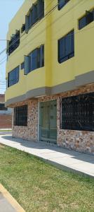 a yellow building with a green door on a sidewalk at ica wasi hostel in Ica