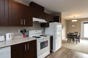 uma cozinha com armários castanhos e um forno de fogão branco em The Killick Inn & Suites em Arnold's Cove