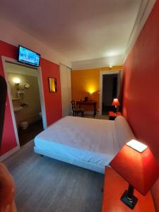 a hotel room with a bed and a desk with a television at Hotel du Cygne in Beauvais