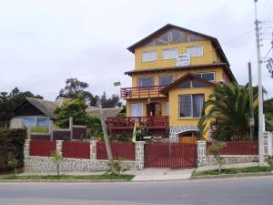 a yellow house with a red fence in front of it at Hostal Libertad in El Quisco