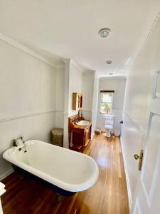 La salle de bains est pourvue d'une grande baignoire blanche et de parquet. dans l'établissement Beautiful beach house on Prince's Grant Estate, à Blythedale