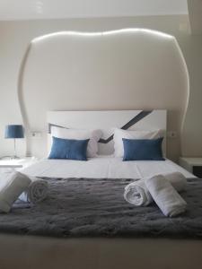 uma cama branca com almofadas azuis e toalhas em Hotel Termas em Chaves