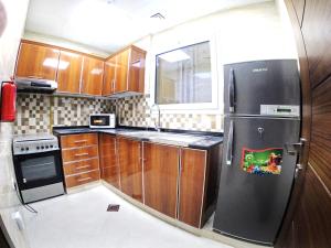 cocina con armarios de madera y nevera negra en Karama Star Residence (Home Stay), en Dubái