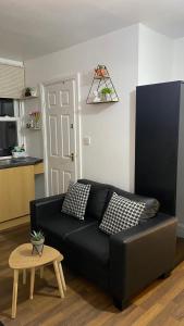 a black couch in a living room with a table at BvApartments Queensgate 4 in Huddersfield