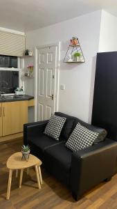 a black couch in a living room with a table at BvApartments Queensgate 4 in Huddersfield