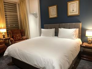 um quarto com uma grande cama branca e uma cadeira em The Gaydon em Lytham St Annes