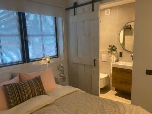 een slaapkamer met een bed, een wastafel en een spiegel bij Vakantiehuisje het kiekje in Bergen op Zoom