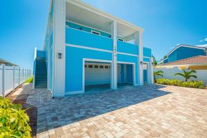 a blue house with a garage on a brick driveway at NEW LISTING! Luxury Beachfront Home - DIRECT Beach Access in Cocoa Beach