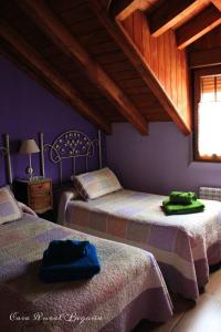 Duas camas num quarto com paredes roxas e uma janela. em Casa Begoña em Igüeña