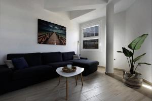 uma sala de estar com um sofá preto e uma mesa em ATICO AUDITORIO CENTRO em La Orotava