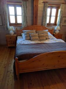 a wooden bed in a bedroom with two windows at Ferienhaus Pfarrerweinzerl in absoluter Ruhelage mit Pool in Kitzeck im Sausal