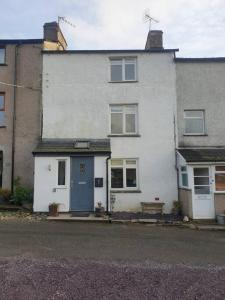 a white house with a blue door and a bench at No8 3 bed cottage Winter Deals offered 3 nights or more Nov-Mar in Backbarrow