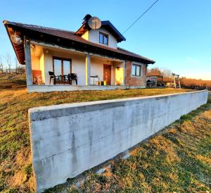 a small house behind a concrete wall at Kuća na dan Vrla strana in Bosansko Petrovo Selo