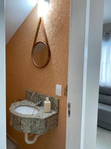 baño con lavabo y espejo en la pared en Sobrado PôrDoSol2 Aconchegante 4 suítes pertodomar, en Guaratuba