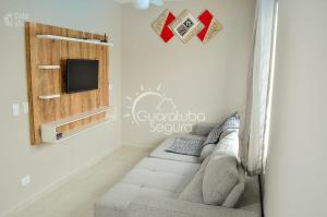 sala de estar con sofá y TV en la pared en Sobrado PôrDoSol2 Aconchegante 4 suítes pertodomar, en Guaratuba