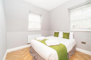 una camera da letto con un grande letto bianco con lenzuola verdi di Stunning Hyde Park Apartments a Londra