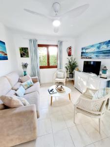 Una sala de estar con un sofá y un televisor. en Apartamentos Delfines, en Cala Blanca