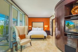a hotel room with a bed and a tv at Luxury Balcony Suite - Across the Beach and Espanola Way in Miami Beach