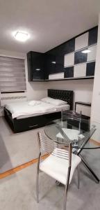 a bedroom with a bed and a glass table and chairs at Apartman De lux Zlatibor in Zlatibor