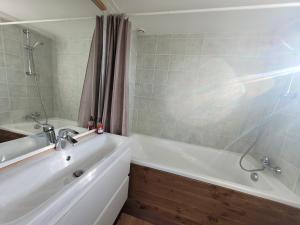 een badkamer met een wit bad en een wastafel bij Gîte de la Doucette in Paimpont