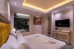 a bedroom with a large white bed with a flat screen tv at Legacy Boutique Hotel in Korçë