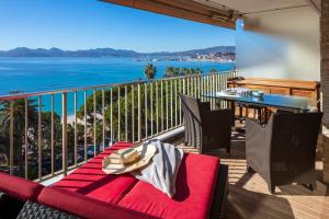 カンヌにあるRabelaisの赤いソファ付きのバルコニーから海の景色を望めます。