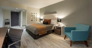 a hotel room with a bed and a chair at Real Inn San Luis Potosi in San Luis Potosí
