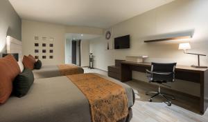 a hotel room with two beds and a desk and a chair at Real Inn San Luis Potosi in San Luis Potosí