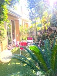 un patio con sedie rosse e un tavolo in un cortile di Maison bijou plage, juan les Pins-Antibes a Antibes