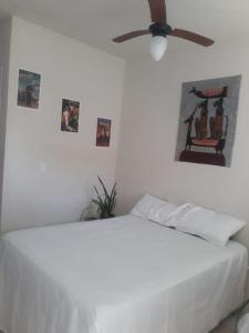 a bedroom with a white bed with a ceiling fan at Casa Verde in Tamoios