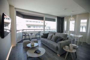 sala de estar con sofá, mesas y balcón en BN SUITES Rambla, en Alicante