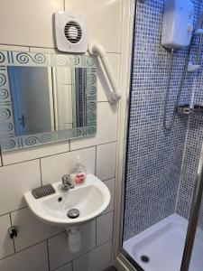 a bathroom with a sink and a shower with a mirror at Gladstone Lodge Guest House in London