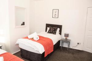 a bedroom with a bed with a stuffed animal on it at Trafford House - Stylish 3-bed home with private parking in Manchester
