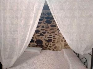 uma cama com cortinas brancas num quarto em La lammia di Pisticci em Pisticci