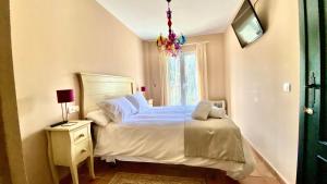 1 dormitorio con cama y lámpara de araña en La Almenara, en Aracena