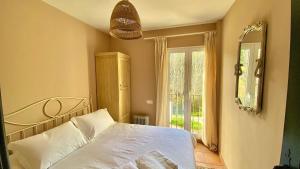 1 dormitorio con cama blanca y ventana en La Almenara, en Aracena