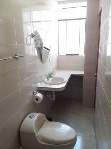 a white bathroom with a toilet and a sink at Hermoso apartamento de estreno en Cajamarca in Cajamarca