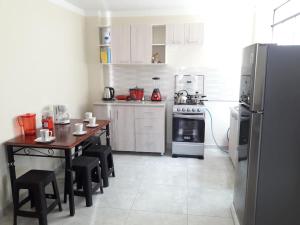 een keuken met witte kasten, een tafel en een koelkast bij Hermoso apartamento de estreno en Cajamarca in Cajamarca