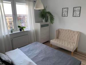 a bedroom with a bed and a chair and a window at Apartament Wanessa in Gdańsk