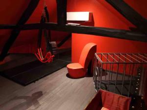 een kamer met een rode muur met een stoel en schoenen bij Loveroom La Parenthèse d ‘Auxerre in Auxerre