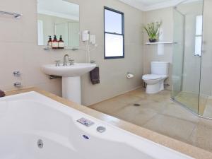 a bathroom with a tub and a sink and a toilet at Something Special 502 Sebel Kiama in Kiama