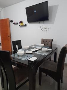 a dining room table with chairs and a television on the wall at Cozy Whole Apartment in Lima