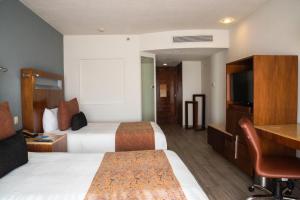 Habitación de hotel con 2 camas y TV de pantalla plana. en Real Inn Guadalajara Expo, en Guadalajara